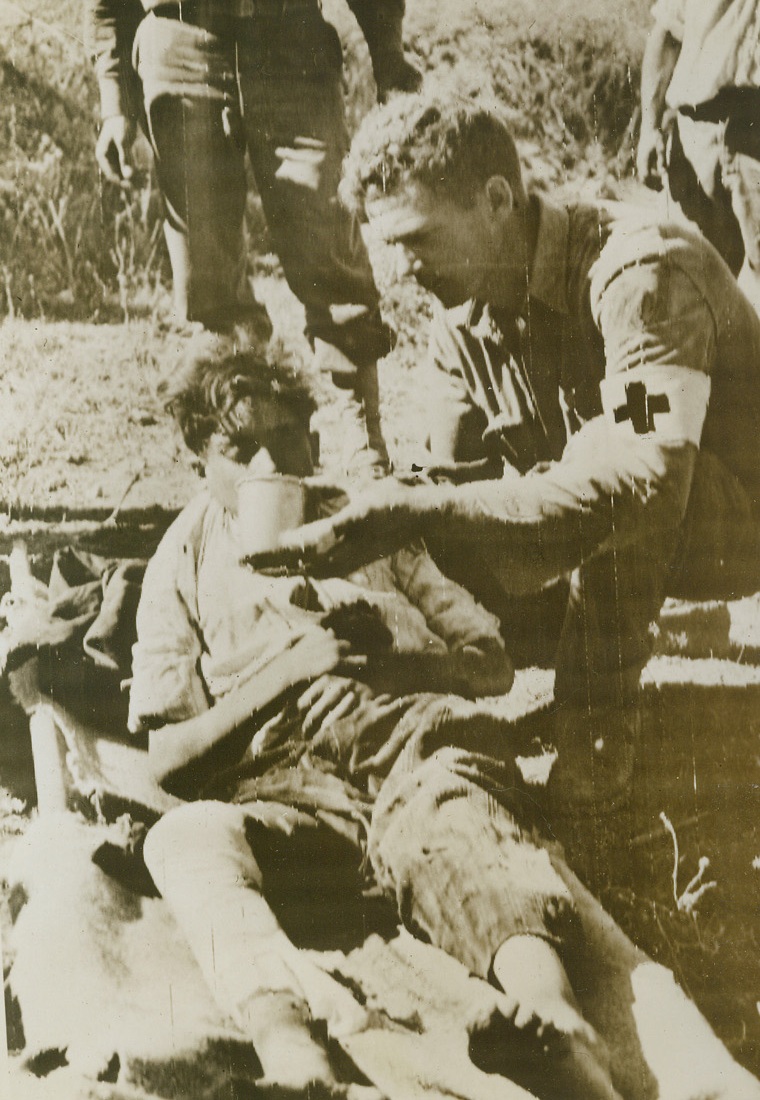 Water for Wounded Lad, 10/8/1943. ITALY -- Cpl. Charles Boss of Okmulgee, Okla., gives water to a wounded Italian youth who was seriously injured while plowing, when he struck a 90mm "dud" shell in the field. The medical corpsman administered first aid to the boy. Credit (U.S. Signal Corps Radiotelephoto - ACME);