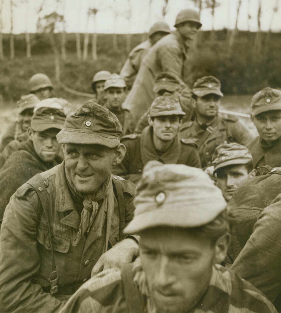 NO FERRYING CHARGE, 10/25/1943. ITALY—Some of these Nazi prisoners look as if they were crossing the River Styx instead of the Volturno, while others seem glad of the “ferry” ride which leads to internment. American soldiers guard the Nazis who are some of Herman Goering’s crack Panzer Grenadiers and the first prisoners taken by the Allies in the sector, being captured less than a mile from the Italian river.Credit: Acme photo by Bent Brandt, War Pool Correspondent;