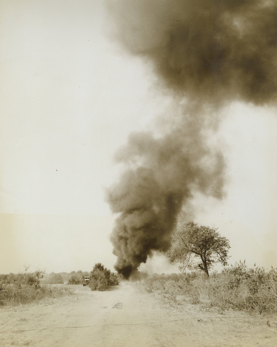 A B-26’S SMOKE, 10/9/1943. ITALY—Returning to an advanced base in Italy after a raid over Naples, a crippled B-26 bomber overshot the field and burst into flames at the end of the runway, sending up a column of heavy black smoke. Miraculously, the entire crew escaped injury and the boys are now ready to fly again. Credit: Photo by Charles Seawood, Acme photographer for War Pool;