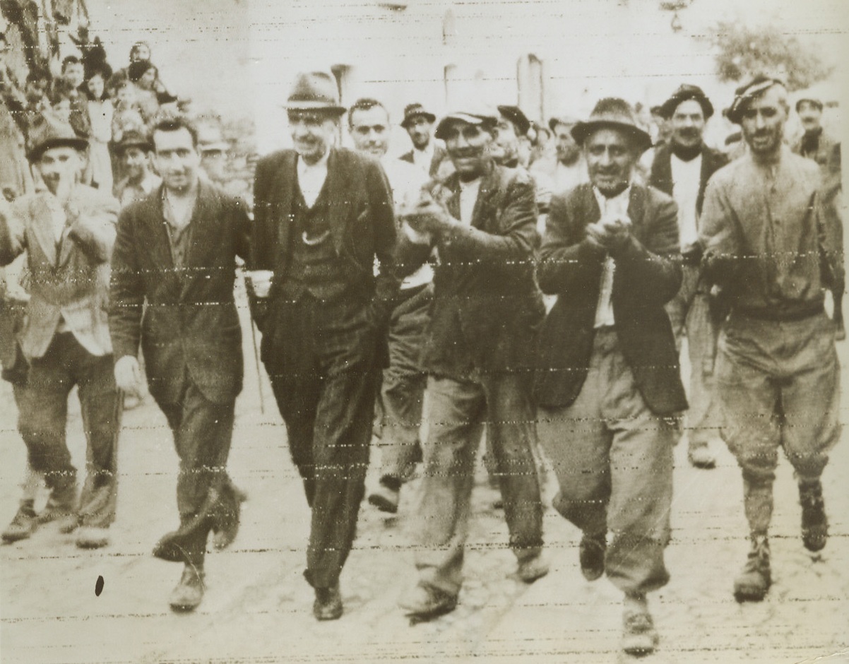 New, Anti-Fascist Mayor, 10/15/1943. CASTILLICCIO DEI SAURI, ITALY – Unanimously chosen Mayor of Castilliccio Dei Sauri by natives after Fascist Mayor had been removed, Enrico Micuoci (with hands in pockets) is escorted through the town by his neighbors. Micuoci was noted for his anti-fascist attitude throughout Nazi occupation of the town. Photo radioed to New York today (Oct. 14th) from Algiers Credit (British Army Photo via OWI from Acme);