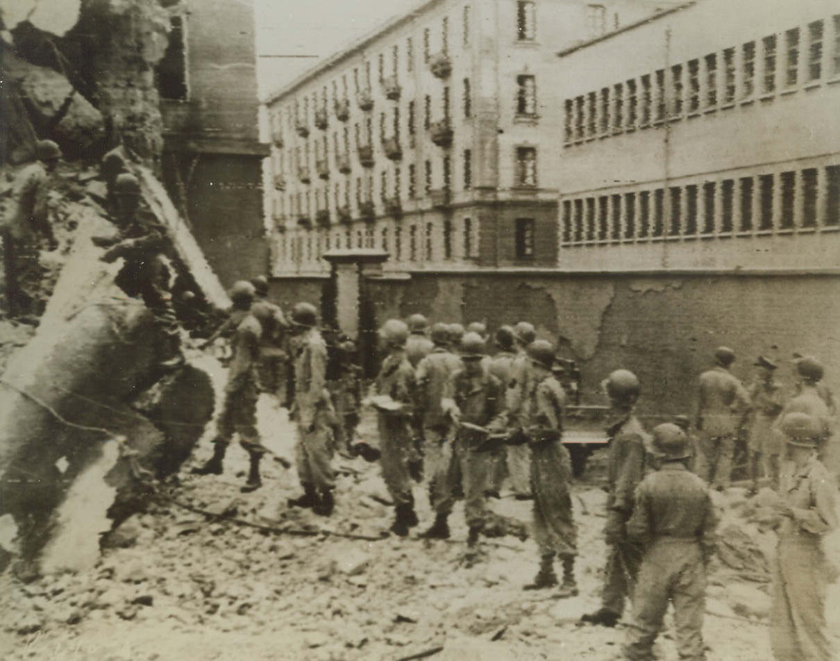 Seek Blast Victims, 10/16/1943. NAPLES – Unable to use tools for fear of further injuring men trapped under wreckage, soldiers pass debris back from man to man in their search for injured who are buried in blasted U.S.-occupied barracks that was demolished by a Nazi time-bomb in Naples. The retreating Germans leave behind their deadly booby traps as the Allies push on. Credit – WP- (ACME Photo Via Signal Corps Radiotelephoto);
