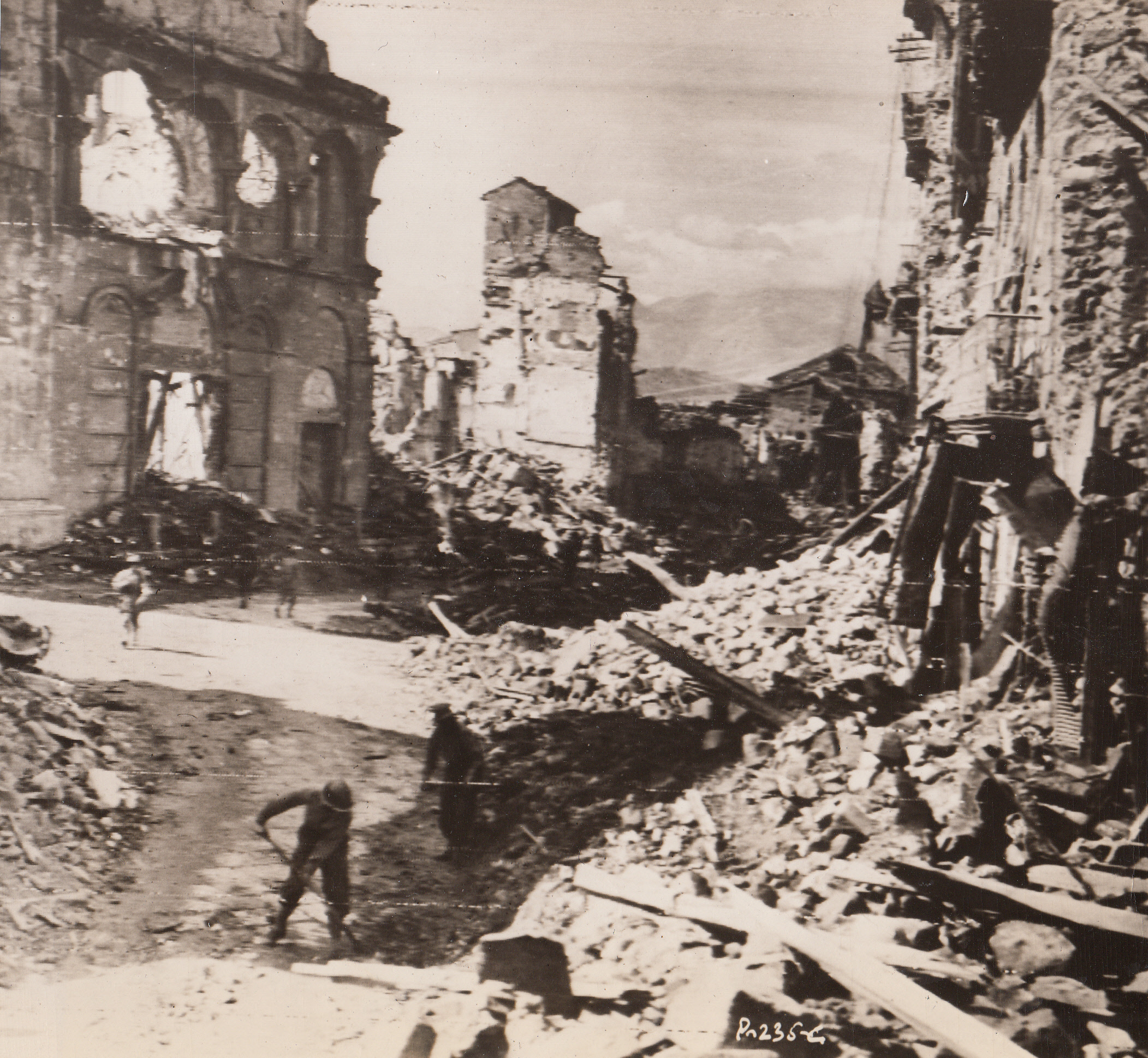Road to Ruin Leads to Rome, 10/13/1943. BENEVENTO, ITALY – A few gutted buildings and streets piled high with rubble is all that is left of Benevento, one of the towns leading to Naples. Army engineers clear a road through the ruins while, in the background, American infantrymen press on toward the next town.;
