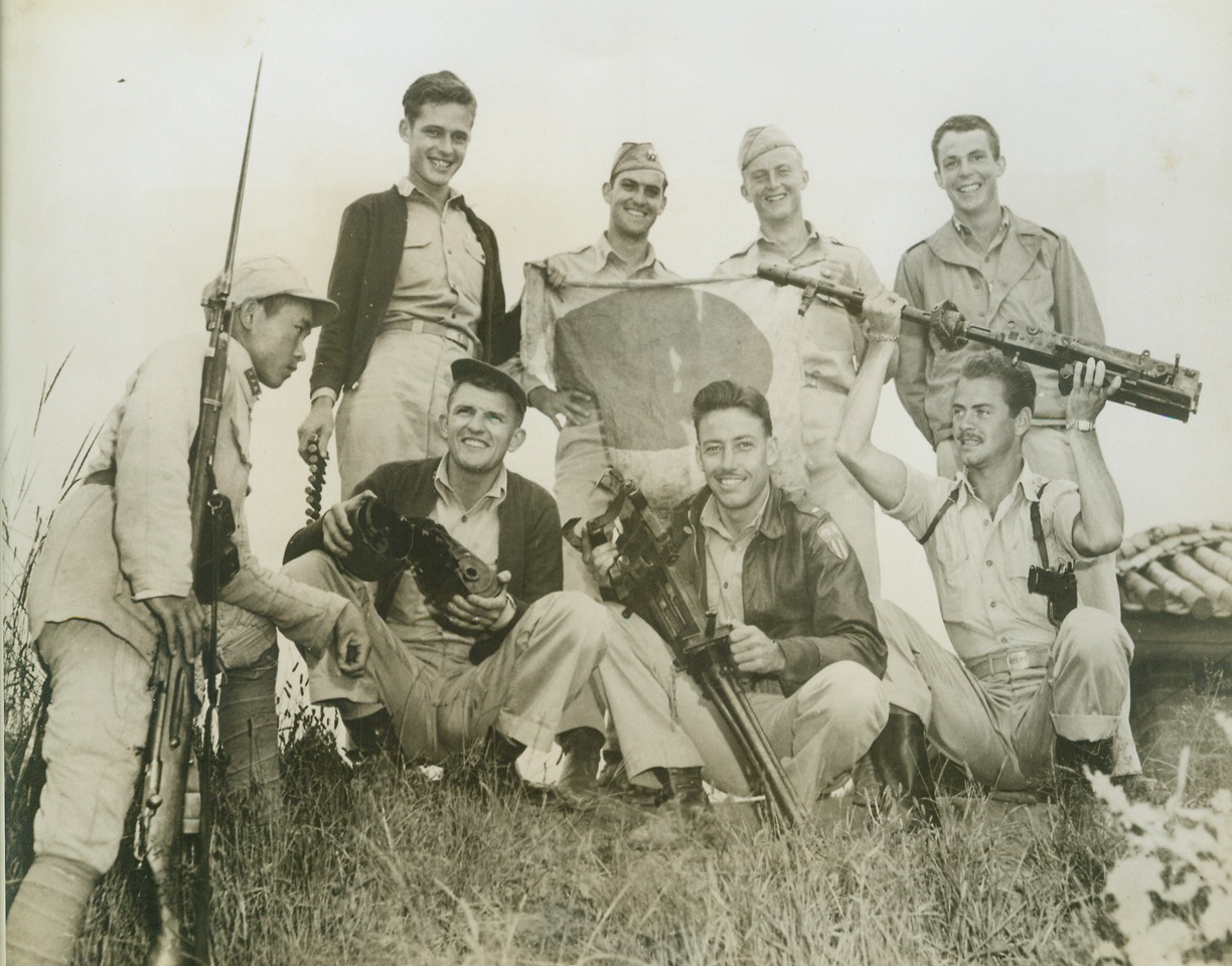 THEY SLUGGED IT OUT, 10/22/1943. CHINA—These smiling fighter pilots slugged it out with Jap airmen when the Nips called at the headquarters airfield of Gen. Chennault’s 14th Air Force. Although the Japs intended to wipe out the airfield, in celebration of their “Aviation Day” (Sept. 20th), they suffered the heaviest losses they’ve ever had in air combat over China. Chatting with a Chinese soldier, the airmen exhibit trophies of the raid: (left to right) front row: Capt. Matthew Gordon, Pueblo, Col., who shot down 1 confirmed and 1 probable; Lt. Curtis L. Scoville, Kansas City, Mo., who got one bomber; Lt. Don Glover, Olympia, Wash., one bomber; rear: Lt. Donald Brookfield, Bryn Mawr, Pa., 1 bomber, 1 Zero; Capt. Roger Pryor, Starkville, Miss., 2 confirmed and 2 probables; Lt. Vernon Tanner, Dallas, Tex., one bomber; and Capt. William Grosvenor, Providence, R.I., 2 confirmed and 2 probables. Credit: Acme;