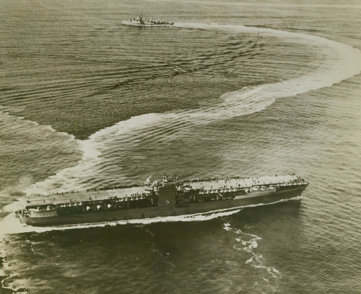 SMALL ESCORT FOR BIG CRAFT, 10/22/1943. AT SEA—One would think that an escort should be bigger and stronger than its charge, but in naval warfare a smaller, and for that reason swifter, escort is desirable. From one of the planes flying above an aircraft carrier, comes this interesting camera study of a modern flat-top and one of its destroyer escorts. Credit: Official US Navy photo from Acme;