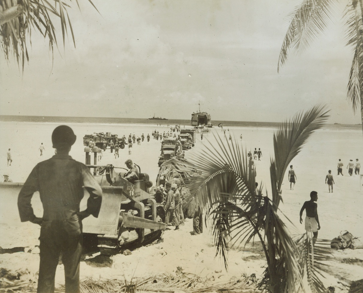 Marines Take Another Pacific Isle, 10/4/1943. Nanumea, Ellice Islands – United States Marines occupy the island of Nanumea, which looks like a tropical poster but is vitally placed for our Pacific offensive. Under protection of U.S. Destroyers, a stream of men and supplies comes ashore from a landing craft at the island in the Ellice group September 4. Credit: U.S. Marine Corps photo from ACME;