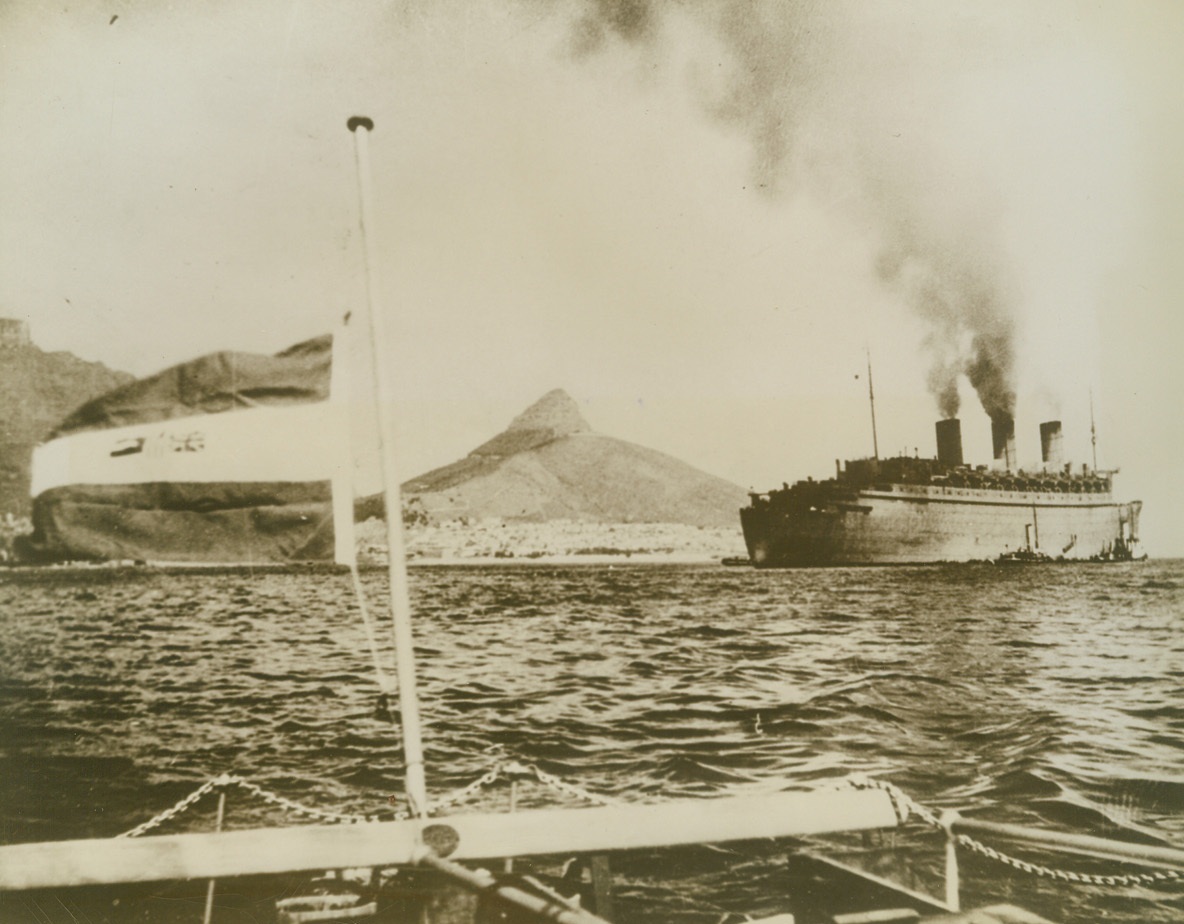 Queen of the Seas Does Her Bit, 10/2/1943. Cape town, South Africa - - Wearing her drab wartime coat of gray paint, the 81,235-ton liner Queen Mary rides at anchor in Table Bay, at Cape town.  The British government has just released this photo of the giant ship, shown soon after she carried a load of American soldiers from New York in a record run of 12 days.  Nineteen days was the previous mark.  The Queen of the seas once sped through a submarine pack so fast that none could torpedo her.Credit line (ACME);