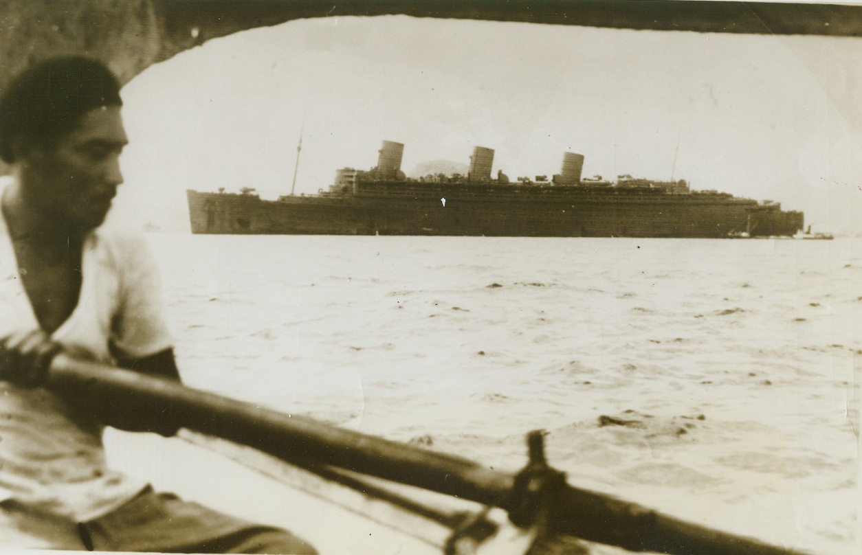 Queen Mary in War Paint, 10/2/1943. Rio de Janeiro -- Wearing her drag, gray coat of war paint, the former luxury liner Queen Mary is shown in Rio de Janeiro harbor. Made some time ago, this photo has just been cleared for release by the British government. At the time, she was carrying American soldiers on a regular 12-day run from New York to South Africa. Credit: ACME;
