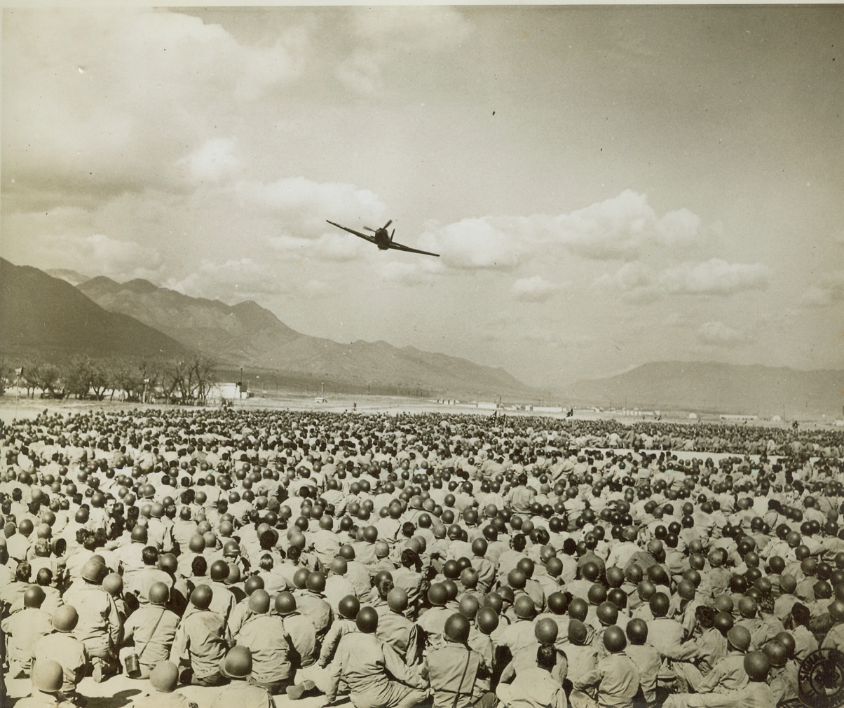 Helmets, Not Mushrooms, 10/28/1943. Camp Carson, Colorado—These thousands of soldiers at Camp Carson, Colo., let “chow time” come and go unnoticed during a 3-hour plane identification experiment staged by fighter and bomber planes of the 3rd Air Force. Lieut. Ted Timberlake, who planned the demonstration, told the soldiers, “All you have to do is recognize all friendly aircraft and shoot down anything else that flies.”  Credit: Official U.S. Army Signal Corp photo;