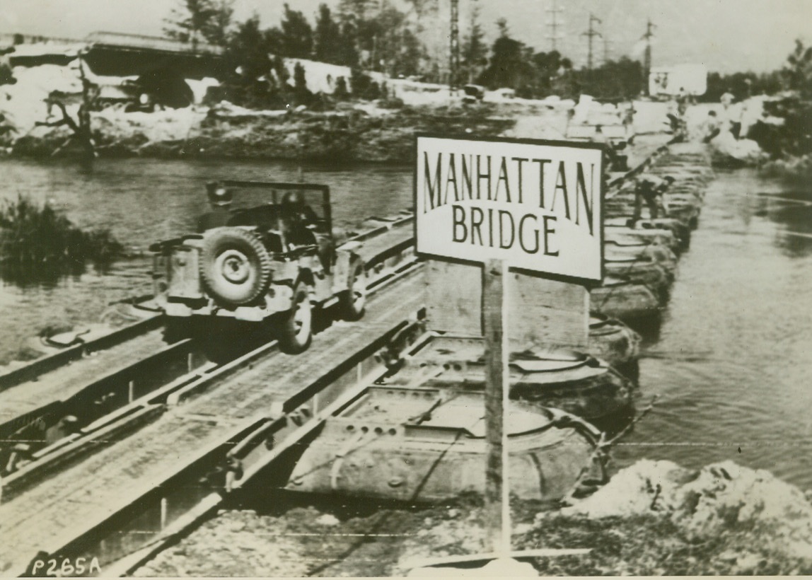 A BIT OF OLD NEW YORK, 11/5/1943. ITALY—This “Manhattan Bridge” is…from its name-sake that crosses the…The pontoon version  spans the Vol…is sturdy enough to be used by…To the left may be seen the…original stone bridge, east of…demolished by the retreating…Credit: Acme photo by Bert…War Picture Pool via Army…;