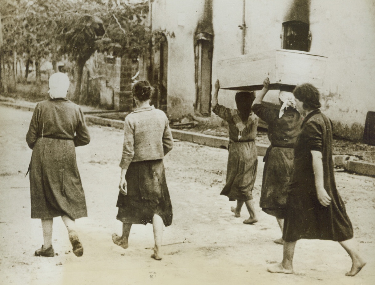 Few Mourners, 11/29/1943. TRAGONE, ITALY—Only a handful of friends—all but one of them barefooted—take part in these simple rites for the innocent victim of warfare in Italy. The crude box, carried by two of the women, contains the body of the mother of two children, who was killed as the Germans retreated through Tragone. Many civilians—including women and children—lost their lives as the tide of battle swept over this part of Italy. Credit: U.S. SIGNAL CORPS photo via OWI from ACME.;