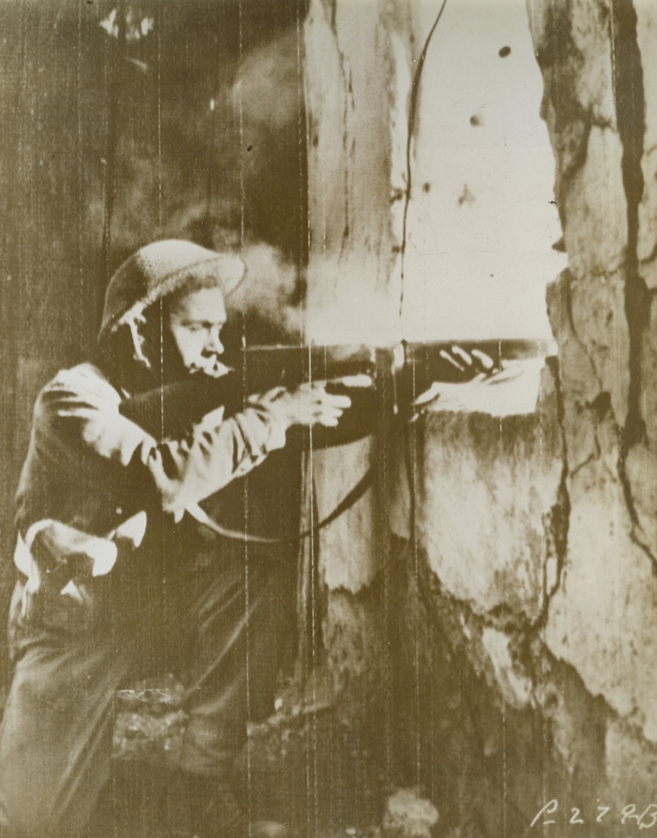 British Sniper in Action, 11/16/1943. CUPA, ITALY—A British sniper in the ruins of a building in Cupa, a few miles from the Gariglaino River, draws a fine bead with his tommy gun through a window. Allied snipers placed in strategic spots in newly captured towns, helped to wipe out many enemy sniper and machine gun nests, as the Allies moved North. Credit: U.S. ARMY RADIOTELEPHOTO from ACME.;
