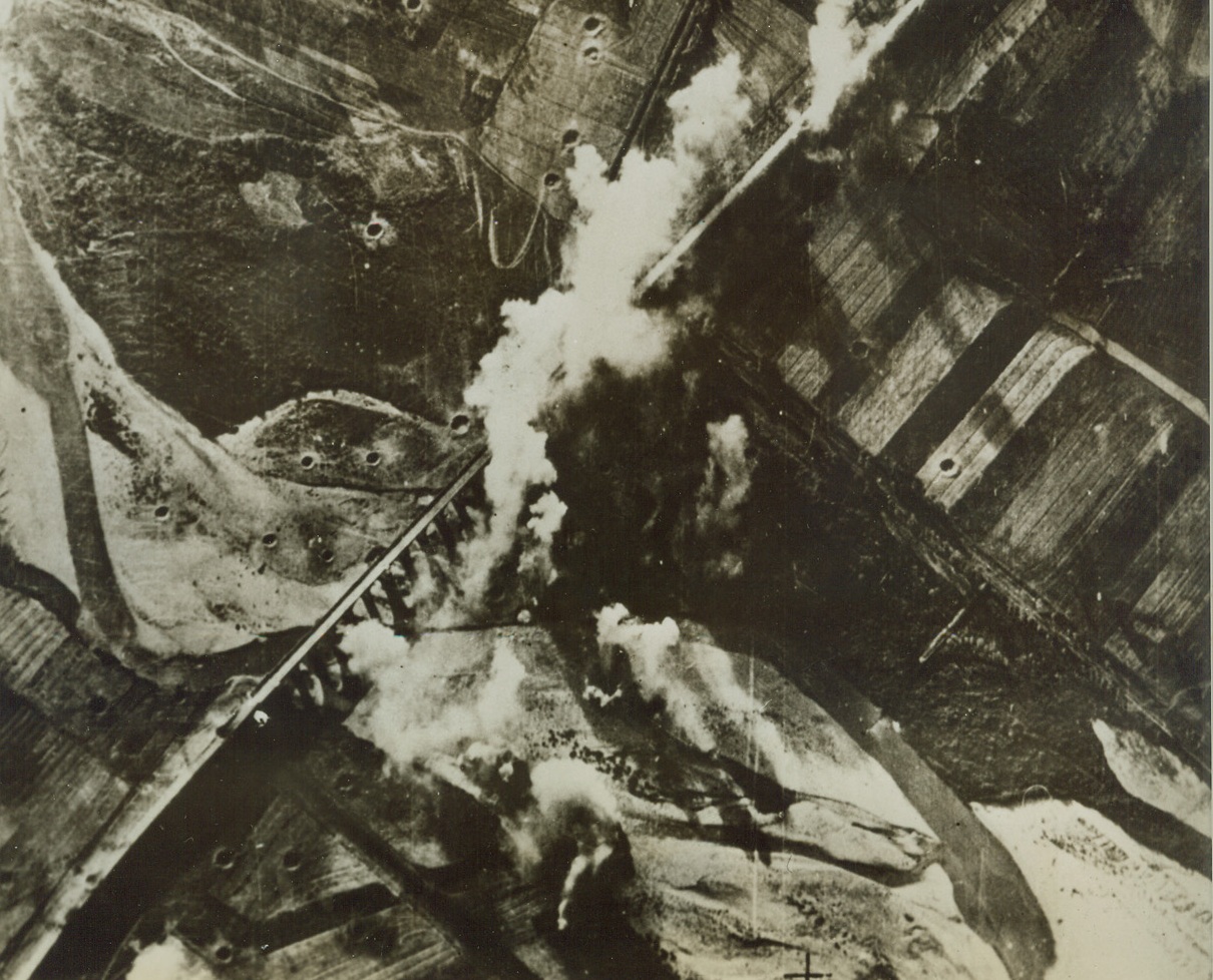 Blasting Enemy Communications, 11/16/1943. ITALY—Bombs from light bombers of the British South African Air Force explode around this vital bridge over the River Sangre in Eastern Italy. On either side of the bridge, crater from previous bomb blasts, can be seen. Credit: ACME.;