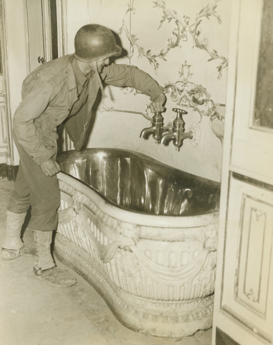 For Scrubbing the Royal Back, 11/17/1943. NAPLES—The hot and cold brass faucets are of heroic size but the tub itself seems a wee bit cramped in the royal bathroom in one of the King’s palaces in the Naples area. Cpl. William Polzin, Chicago, Ill., tries out the luxurious bath fixture. The Baroque tub is lined with brass, too. Credit: ACME photo by Bert Brandt, War Picture Pool Correspondent.;