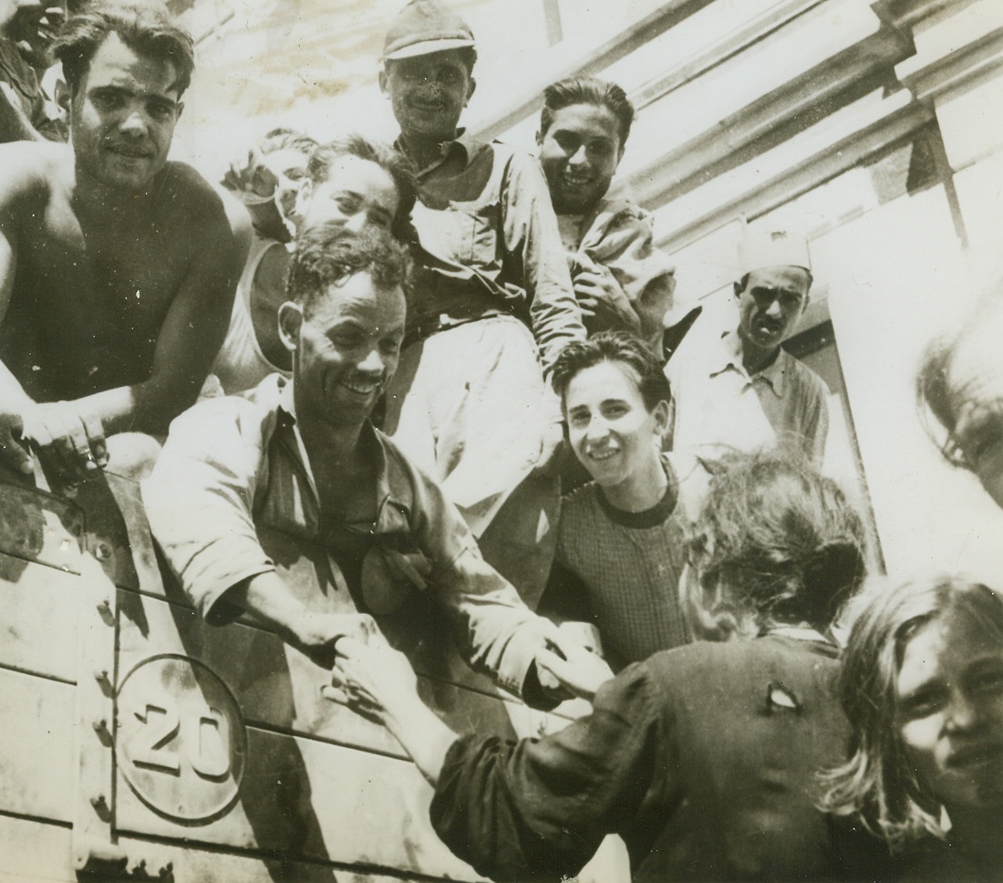 Homecoming, 11/17/1943. SICILY—Smiles wreath the faces of former Italian prisoners of war as they greet their wives, sisters, mothers and sweethearts on their return from Allied prison camps. With the war over for them, Sicilians are now returning to normal, picking up the threads of their old lives and rebuilding the shattered country. Credit: OFFICIAL OWI Photo from ACME.;