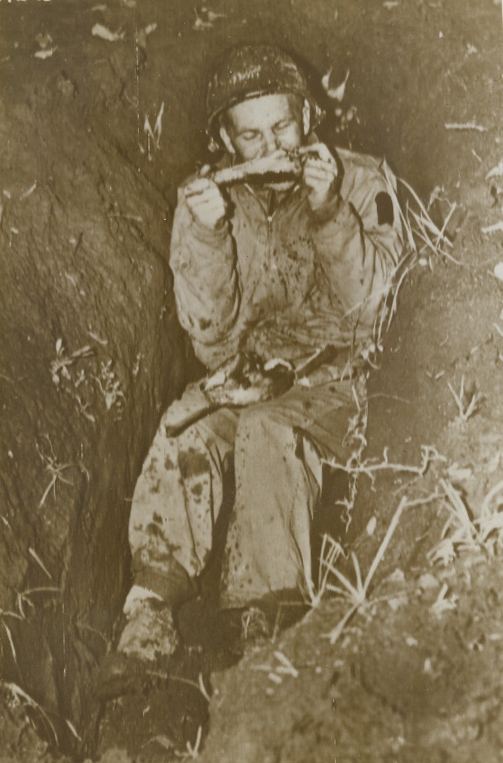 THANKSGIVING DINNER IN A FOXHOLE, 11/27/1943. SOMEWHERE IN ITALY—In a foxhole, near the fighting lines in Italy, Pvt. Don Finholm of Ludington, Mich., digs into a turkey drumstick on Thanksgiving Day, while a full mess kit rests in his lap. Hot dinners were rushed to every man at the front, via truck, mule pack, and even personal courier, so that every Yank might enjoy the traditional Thanksgiving feast.Credit: Photo by Acme photographer for War Picture Pool, Bert Brandt, transmitted by Signal Corps Radiotelephoto;
