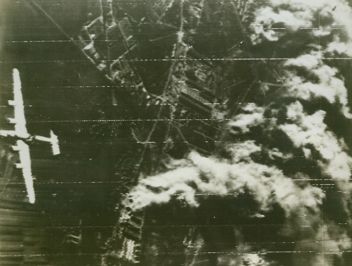 DOOMED U.S. BOMBER, 11/8/1943. A consolidated B-24 Liberator of the U.S. 15th Air Force, a huge hole smashed in its fuselage just abaft the wing, leaves the smoking target, the Weiner Neustadt aircraft plant near Vienna, during the raid last Nov. 2. Just after this photo, which was flashed to the U.S. by Radiotelephoto today, was taken, the ship went into its death dive. Heavy flack blasted the hole and doomed the Liberator. Credit: U.S. Army Air Forces photo via U.S. Signal Corps Radiotelephoto from Acme;