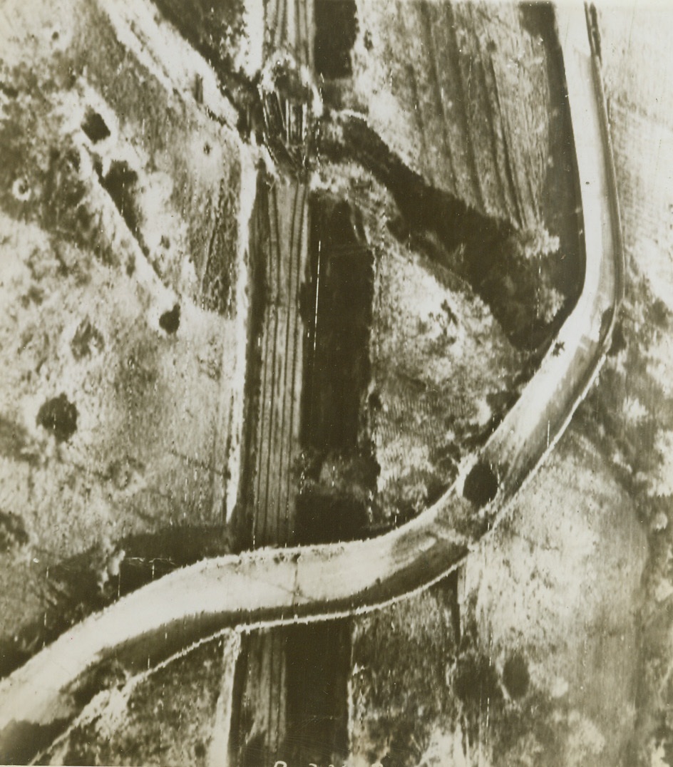 PRECISION BOMBING, 11/17/1943. The score card of precision bombing is clearly marked in this aerial photo of a bombed railway line and road at Staz-de-Toro-Presenzano, Italy. Direct hits on a railroad trestle and on the road can be seen, while near hits pock-mark the area around the objective. Credit: Photo by Charles Seawood, Acme photographer for War Pool, via U.S. Signal Corps Radiotelephoto;