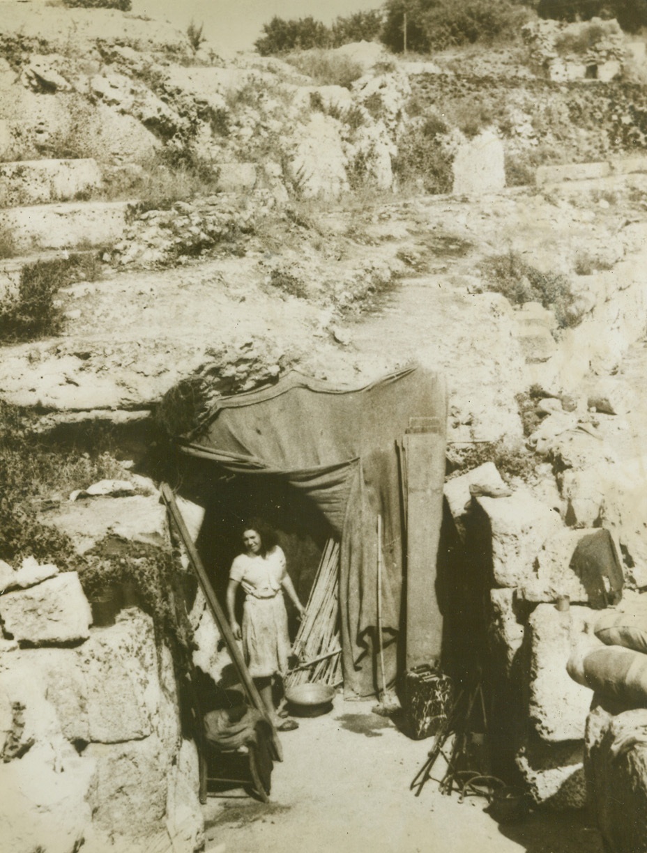 HER AMPITHEATRE [sic] HOME, 11/17/1943. SICILY—This huge Roman ampitheatre [sic] was “home” to many Sicilian families during the first few days after the Germans were driven from Sicily. With their houses broken and bomb-wrecked, natives had to take cover in makeshift homes like this until their former homes could be rebuilt. Credit: [illegible] from Acme;