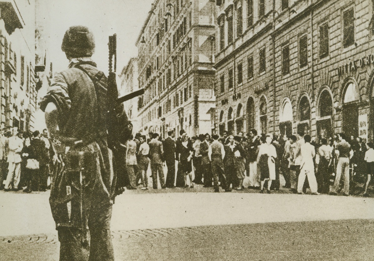 They Remember Naples, 11/8/1943. Rome, Italy – Natives, (background), in this street in Rome, remember the rape and pillage of the once-beautiful city of Naples by the Germans, and avoid this heavily-armed Nazi paratrooper, (left foreground) as if he had a deadly plague. Since the Germans turned on the Italians after the armistice shooting many down like dogs, Italian hate of Nazis has steadily grown. This photo, released in New York today, is from a neutral source. (Passed by censors). Credit Line (ACME);