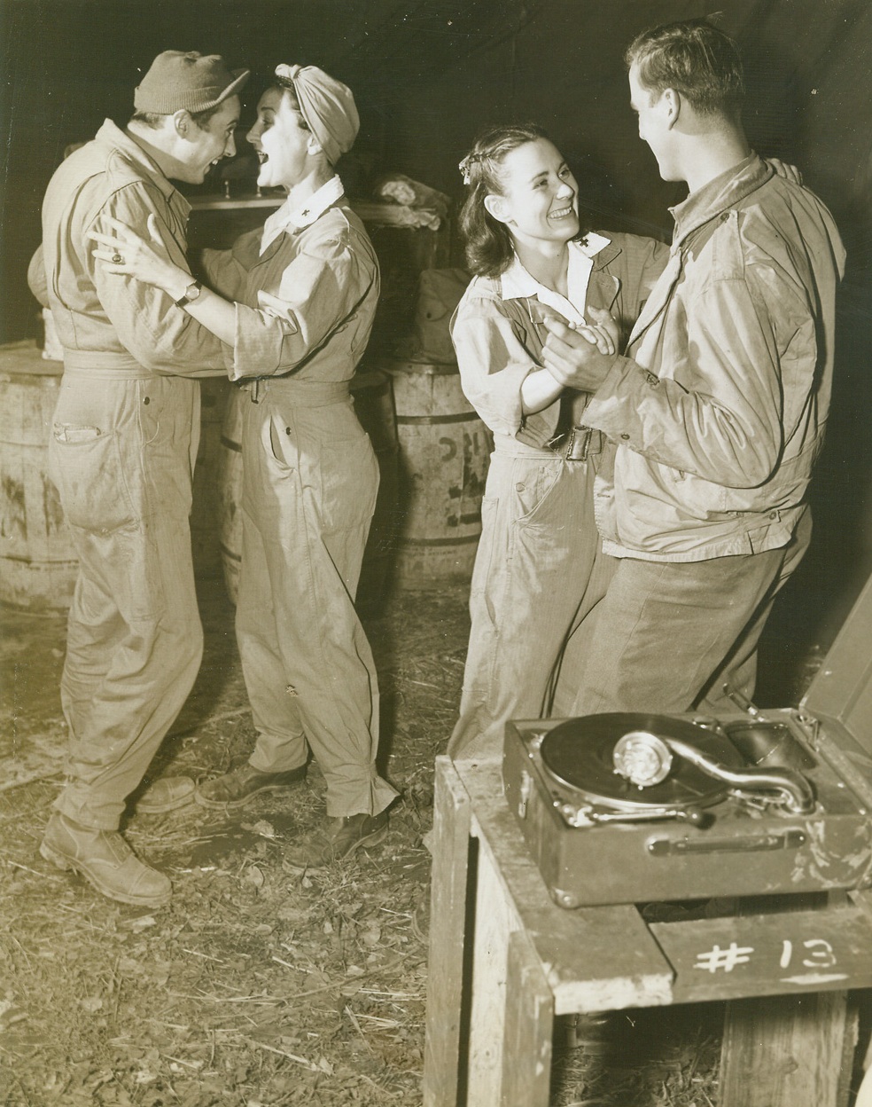 Frolic at the Front, 11/28/1943. SOMEWHERE IN ITALY -- It's a festive occasion at the Italian front as the guys and gals drag out a portable phonograph and cut a figurative rug on foreign soil. At left, dancing with Lois Berney of Fallon, N.C., is Pfc Clyde Burgess of Tolcoa, Ga. Dancing at right are Mary Ross Mohen of Unawa, Iowa and Pvt. William Maderra of Rayland, Ohio. The girls are Red Cross workers whose job is to boost the morale of Fifth Army men.  Credit Line - WP - (Photo by Bert Brandt, Acme Correspondent for War Picture Pool);