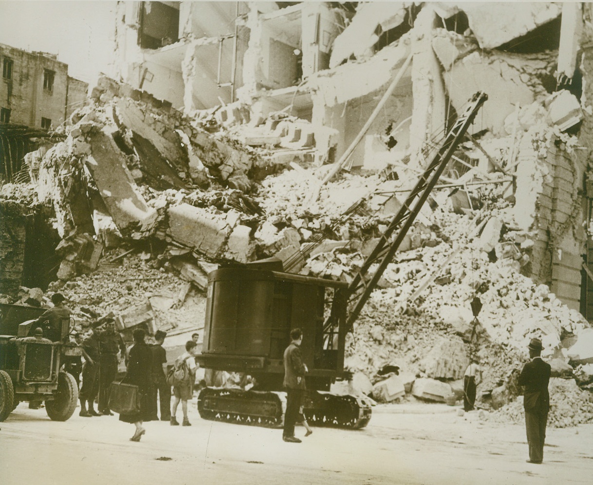 Cleaning up Naples, 11/2/1943. NAPLES, ITALY – Working with crane and dump trucks, Allied engineers clear away debris from bombed buildings in Naples. The work of rehabilitating the city goes on while fighting Allied troops push on to the north. Credit (PWB Photo from OWI via Acme);