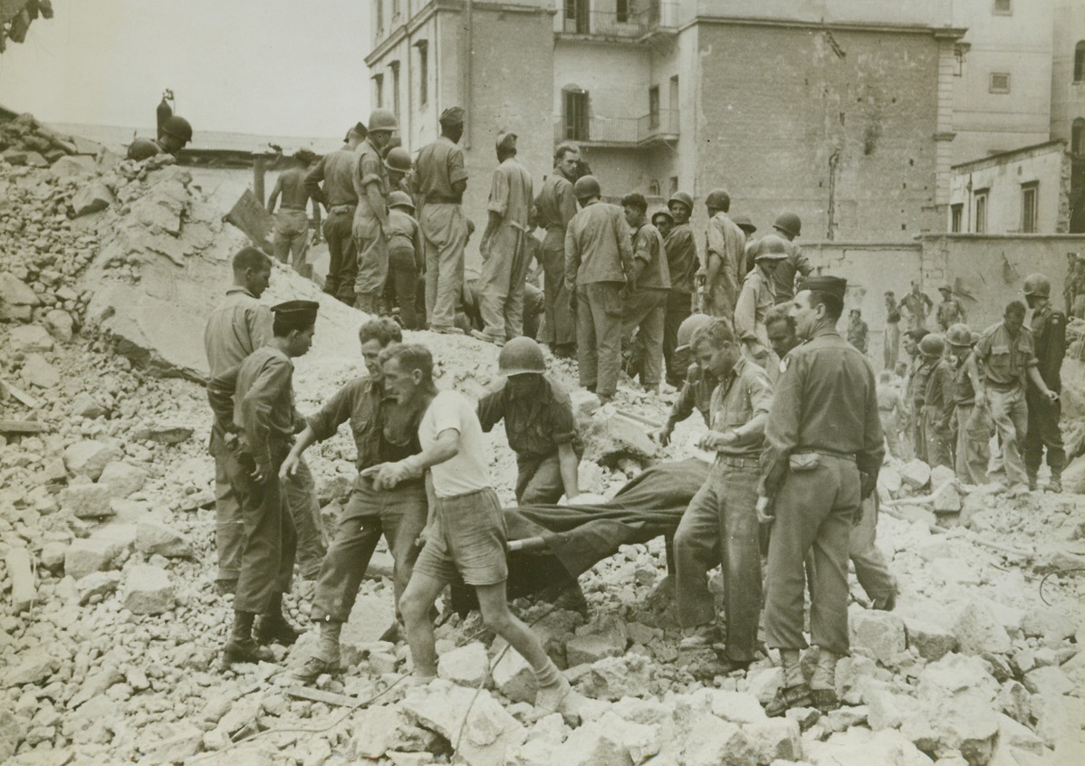 PHOTOS ON SECOND NAPLES BLAST, 11/2/1943. This photo, just released in the United States, was taken three days after a German time bomb demolished a corner of the post office in Naples, when another Nazi-planted land mine exploded under a wing of an artillery barracks in Naples, where hundreds of American paratroopers were quartered. Some 1,000 pounds of dynamite cached deep underground blew up killing more than 40 soldiers. Here, amid the ruins, soldiers and civilians work feverishly to rescue any living buried beneath the collapsed three floors of the barracks. Credit: Acme;