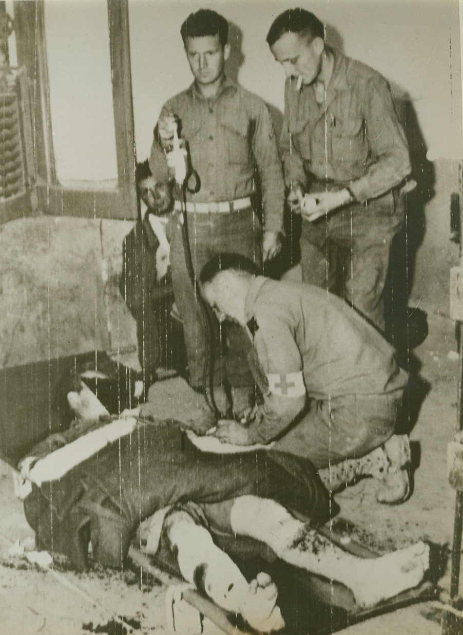 PLASMA FOR AMERICAN SOLDIER, 11/3/1943. A blood plasma injection is given to an American infantryman by medical Captain Hal Ferguson at a front line station hospital in Italy, in this photo flashed to the U.S. by radiotelephoto. Assisting the doctor are, (left to right): Pfc. Everett Rainey, of Mountain Grove, Mo.; and Sgt. Marion Freed of Belleville, Kansas. Credit: U.S. Army radiotelephoto from Acme;