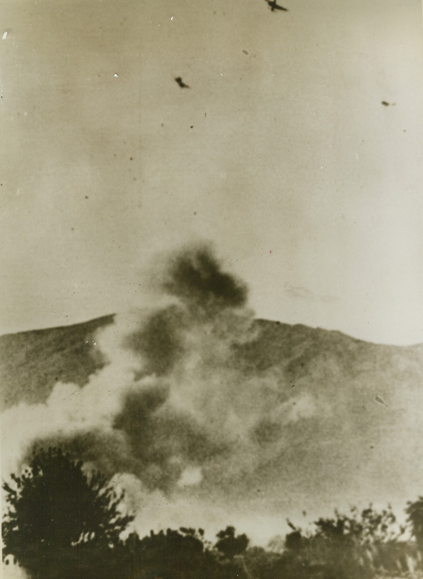 ACTION AT COS, 11/22/1943. Received in New York from Lisbon today, this picture, according to the caption accompanying it, purports to show German bombers of the JU-87 type in action over the Island of Cos, one of the Dodecanese group. This was shortly before the occupation of the island by German troops in a fierce assault. Smoke rises from a hit as the bombers peel around to continue their attack. Credit (ACME);
