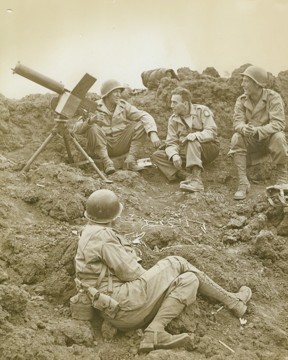 FRONTLINE INTERVIEW, 11/23/1943. WITH THE 5TH ARMY in ITALY—Cy Korman, (center, background), Chicago Tribune war correspondent, interviews members of a frontline machine gun post, located in a ten-foot-deep shell crater along the Italian Front. In foreground, is Pvt. Dallas Jones, of Jacksboro, Texas. With Korman are, Pvt. Frederick Stewart, of Hictonville, Ind. (left); and Pfc. Raymond Kubilek, of Vernon, Texas, (right).  Credit Line (ACME Photo by Bert Brandt for the War Picture Pool;