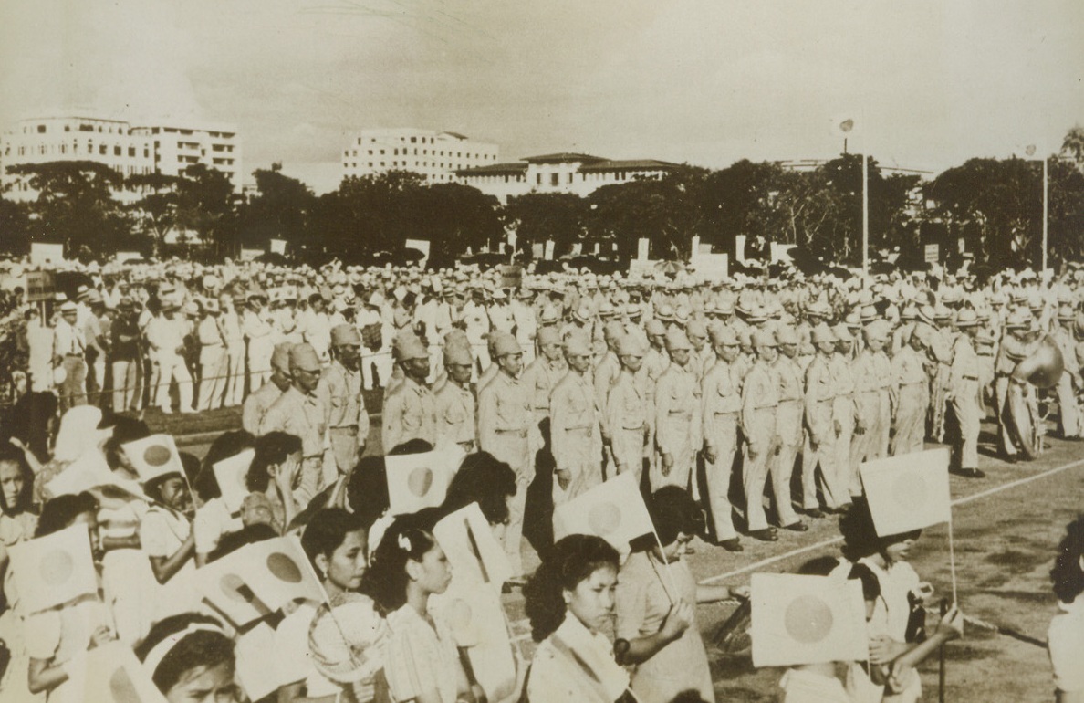 Filipino Youths All for Japan – Japan Says, 11/18/1943. Manila – This Jap-made picture smuggled to the United States supposedly shows Filipino youths (center, uniforms) preparing to sail from Manila for Japan to take up studies fitting them as future leaders in their homeland. In the foreground, Filipino girls wave Jap flags. According to the Japanese caption, the youths represent some of the leading families of the Philippines. The photo was brought out of Japanese-occupied territory by Raymond P. Cronin, an American Newspaperman who was interned at Manila and is now enroute to the U.S. aboard the exchange ship Gripsholm. Credit: ACME;