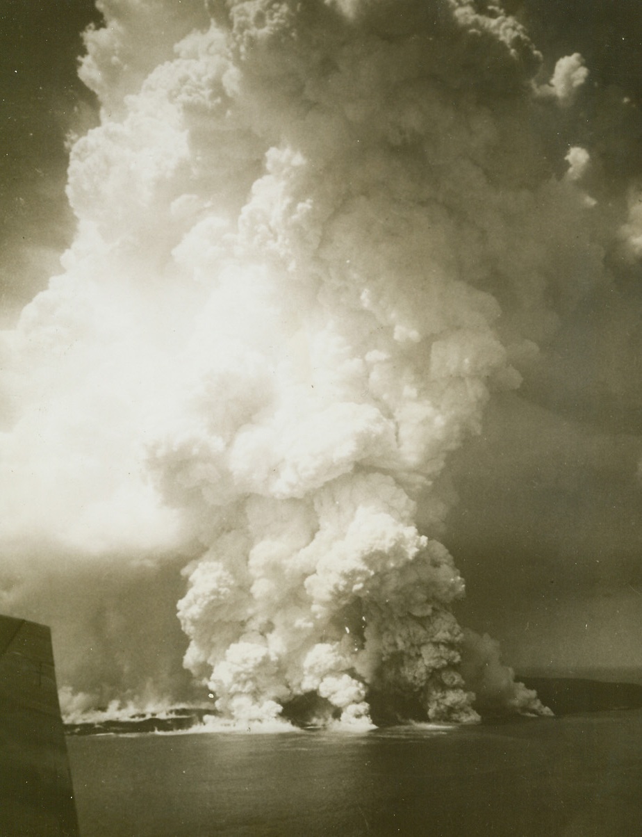 ‘Tin Can’ Island Explodes, 11/30/1943. The volcanic island of Ninafou – known as ‘Tin Can’ – seems to surge upward in its entirety as a giant eruption convulses the tiny isley.  This picture was made just as the towering pillar of smoke and lava rose up over the glassy Pacific by a Navy photographer.Credit Line is illegible;