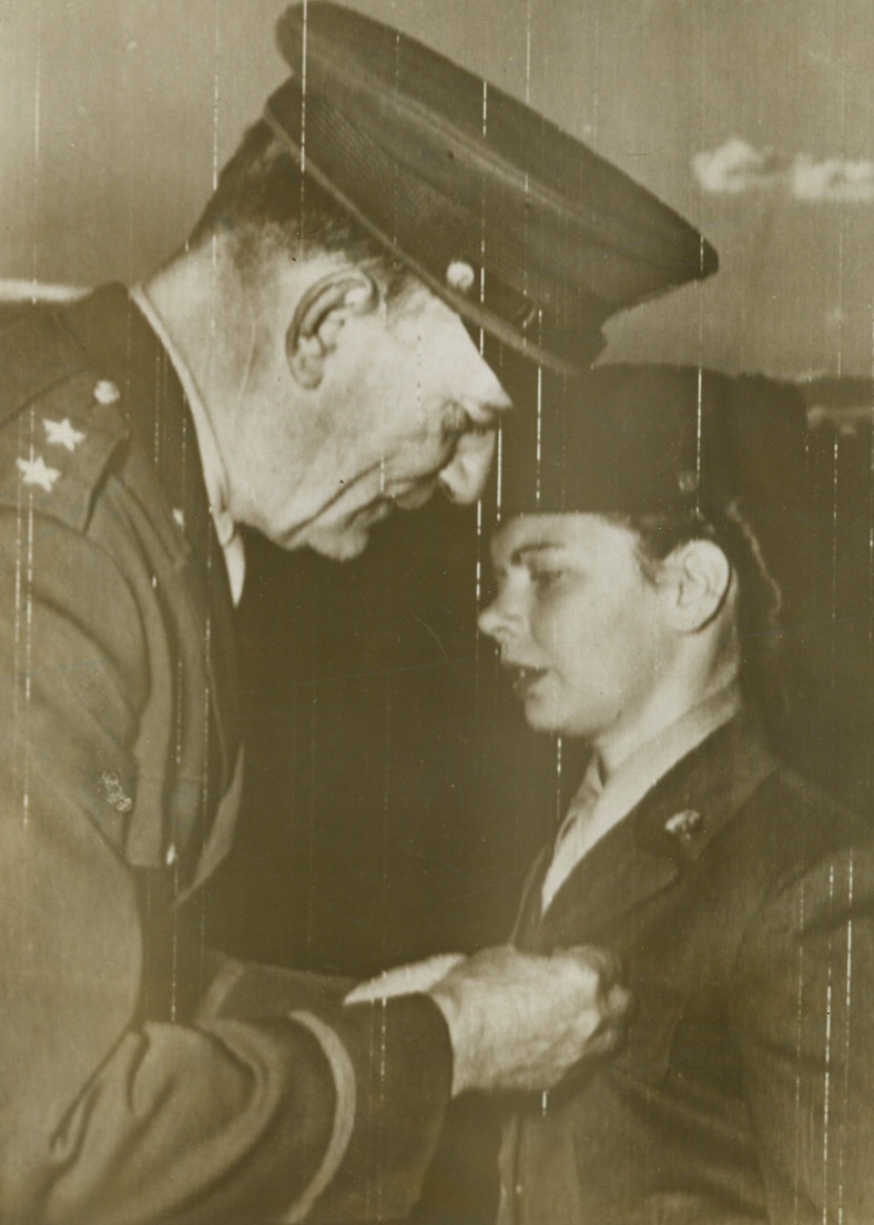 Tiny But Brave, 11/22/1943. Africa – Pvt. Margaret H. Maloney, of Rochester, N.Y., who is so tiny her nickname is “Pee Wee,” receives the soldier’s medal from Major Gen. R.S. Hughes, Deputy Theater Commander, for saving the life of Pvt. Kenneth M. Jacobs, of York, Pa., whose clothes caught fire from spilled gasoline. Pvt. Maloney beat out the flames with her bare hands, and was hospitalized for six weeks.  She is the first WAC to receive the soldier’s medal and as a result, the General kissed her.Credit (U.S. Army Signal Corps radio telephoto);