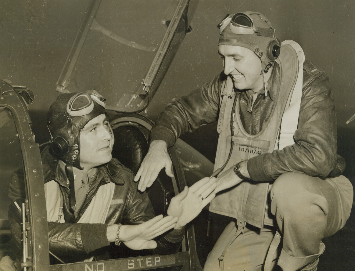 SAID THE LOOIE TO THE COLONEL, 11/4/1943. SOMEWHERE IN ENGLAND – Their hands expressing the story, Lt. Col. Jock Jenkins (in cockpit), listens to the story of Lt. Russell F. Guske, of Port Huron, Mich., holder of an air medal with three oak leaf clusters, and the DFC.  The lieutenant was awarded the decorations for participating in 46 sorties, the destruction of one enemy aircraft, and probable destruction of seven others.   Credit: Acme;