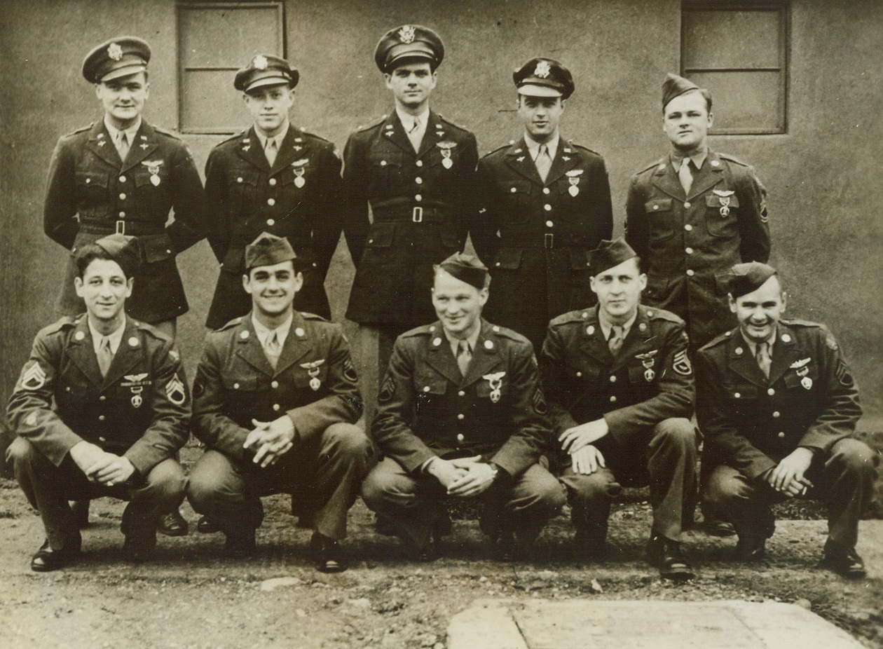 PURPLE HEART CREW, 11/28/1943. SOMEWHERE IN ENGLAND—Every member of the crew of the Flying Fortress “Stupefier” was awarded the Purple Heart Medal, as a result of wounds sustained during a recent raid over Hitler’s Europe. Left to right, the heroes are: (front row) S/Sgt. Jerry Gentile, Williamson, W/Va.; S/Sgt. M.J. Cheramie, New Orleans, La.; S/Sgt. K.H. Barnett, Springfield, Mass.; S/Sgt. Emery Davenport, Gloversville, NY; S/Sgt. E.N. Hobbs, Phila., Pa. (Back row) Flight Officer W.P. Maresh, Valley City, N.D.; Lt. F.L. Mailander, Monticello, Ill.; Lt. R.A. Romme, Chicago, Ill.; Lt. LeRoy Blair, Horton, Kas.; and T/Sgt. A.D. Patterson, Canfield, Ohio. Credit Line—WP—(ACME);