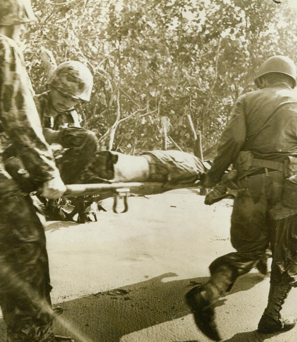 Casualty At Bougainville, 11/23/1943. Bougainville Island -- Buddies rush a wounded Marine to immediate first aid treatment, just off the beach at Bougainville. The Japs succeeded in strafing the small landing boats with machine guns and 20 mm. cannon fire, causing some casualties to the Leathernecks who were churning ashore at the South Pacific Island. 11/23/43;