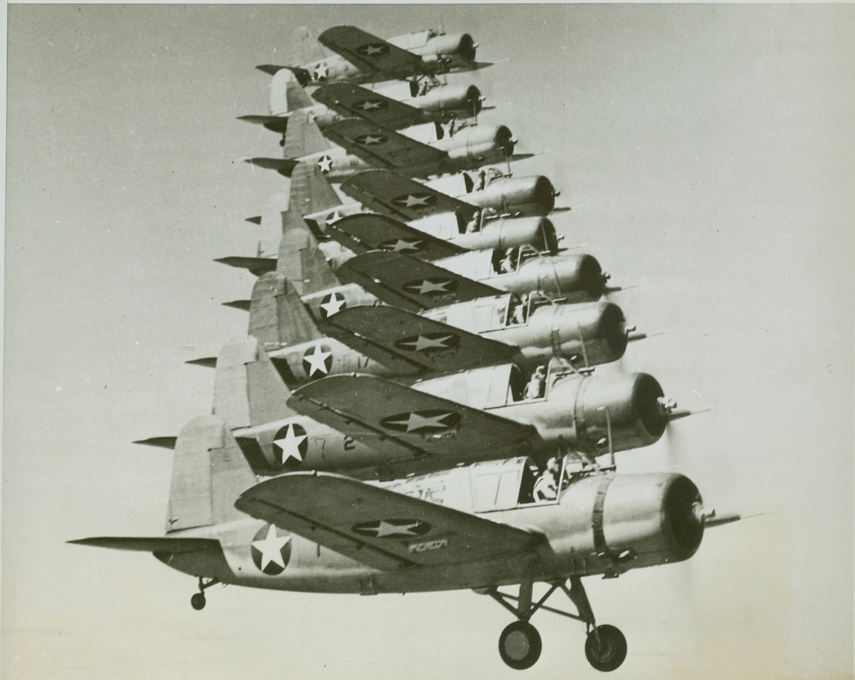 Flying Staircase, 11/9/1943. Nine Kingfisher scout planes (OS2U) of the Navy form a flying “staircase” by flying almost “cheek-to-cheek” during aerial maneuvers. Precision flying is almost matter of fact to Navy fliers.  Credit: Official U.S. Navy photo from ACME;