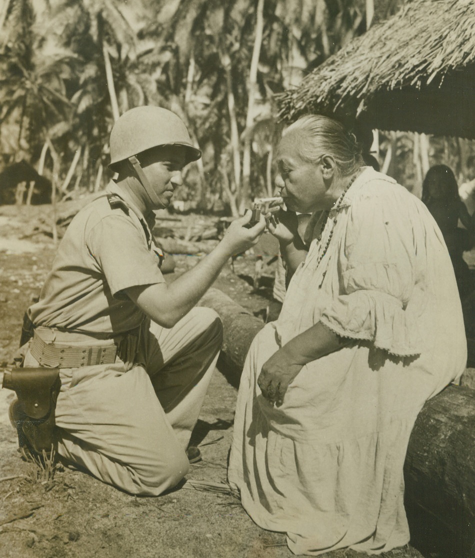 Her Majesty The Queen, 12/17/1943. MAKIN ISLAND – Queen Tabonou, of the Gilbertese Natives, gets a light for her cigarette from Lt. Bruno Raymond, Royal Australian Naval Volunteer Reserves, who was born in the central Pacific islands.  The Queen hadn’t seen Raymond since he was a baby.  He “Visited his home town” after the allies captured  Makin.Credit:  ACME;