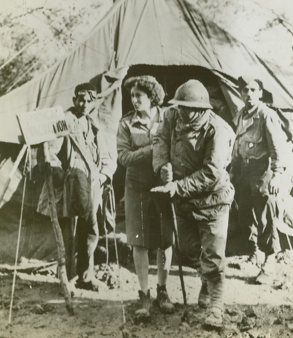 Aided By His Own Countryman, 12/28/1943. Italy – As a wounded French soldier hobbles out of an evacuation medical tent somewhere in Italy, a French woman ambulance driver is there to meet him. She will speed him to a rear medical base for treatment. Credit (U.S. Signal Corps Radio From ACME);