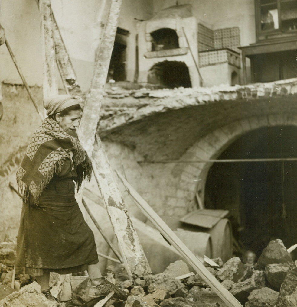 She Stuck It Out, 12/22/1943. Italy—When American troops took over the town of Mignano, they were surprised to see this old Italian woman emerge from the rubble and debris that clogged the streets. She had been living in her home through weeks of shelling and bombing, refusing to be driven from her few prized possessions. The Germans left the Italians very little when they evacuated the area, taking everything of value with them. Credit: ACME photo by Sherman Montrose, War Pool Correspondent.;