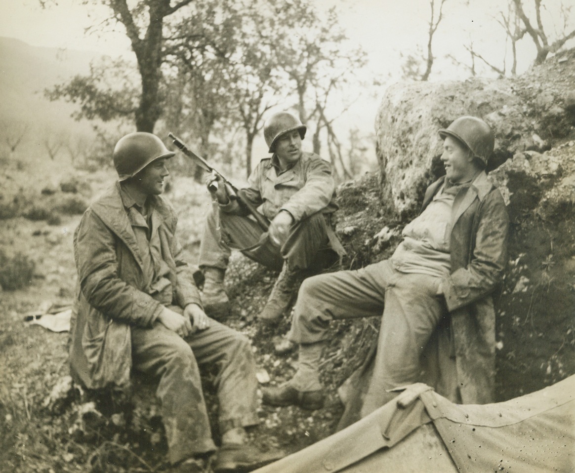 Conversation Piece in Italy, 12/9/1943. A trio of Yanks discuss the fortunes of war by a bomb crater behind the front lines in Italy. Left to Right are: Cpl. F.C. Griffith, Mansfield, Texas; Pfc. Doc Owens, Meigs, Ga.; and Pvt. Eldon D. Long, Dallas, Texas. Credit (ACME);