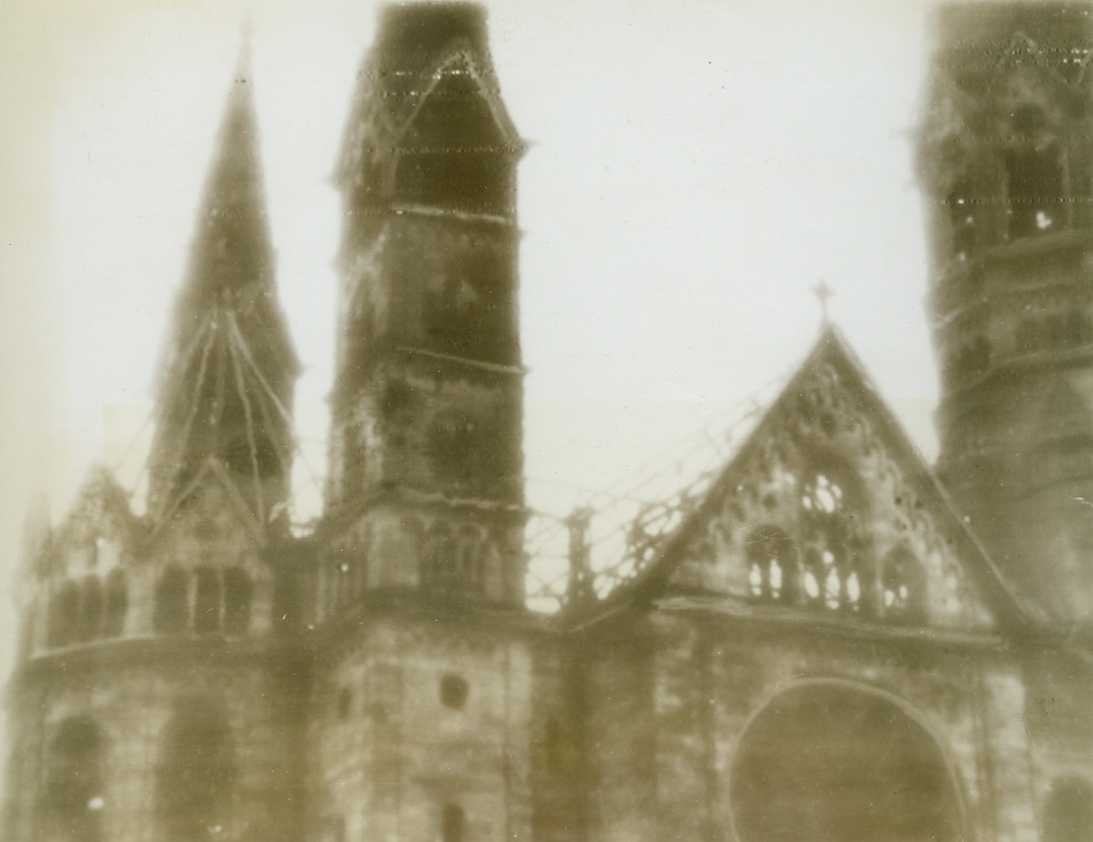 Famous Berlin Church Damaged, 12/13/1943. BERLIN—One of the unavoidable casualties in the all-out allied bombings of Berlin is the Kaiser Wilhelmgedaechtnis Kirche (memorial church), massive Gothic church, on the city’s famed Kurfirstendam, The tall Spires remain standing and most of the damage seems to have been done to the main roof and windows. Photo received by radio from Stockholm this morning.  Credit Line (ACME Radiophoto);