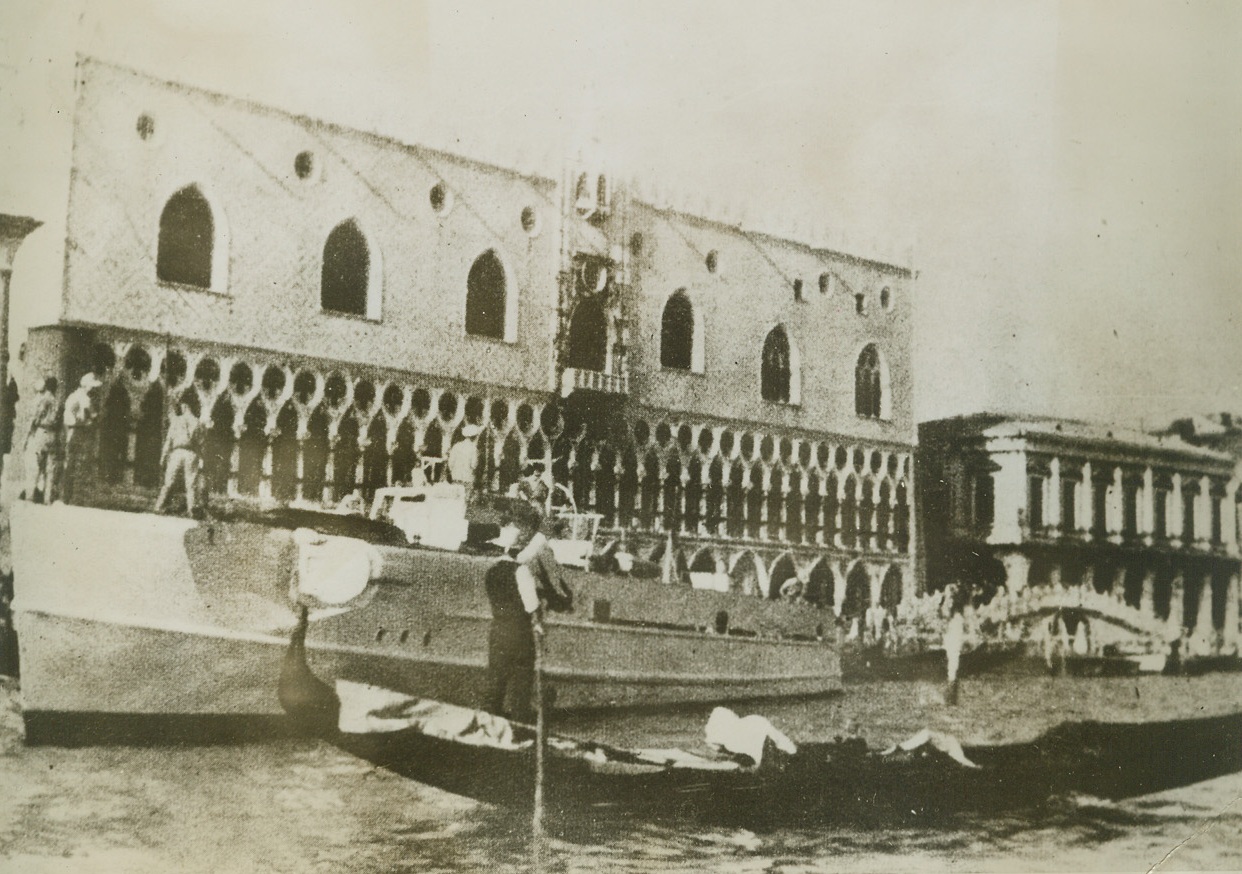 WARTIME “GONDOLA” IN VENICE, 12/13/1943. The historic beauty of Venice’s canals, had been marked by the grimness of war and here in this photo from a neutral source, a German gunboat can be seen anchored near the Doge’s Palace in Venice, alongside a gondola (right foreground) waiting for hire. Credit: Acme;
