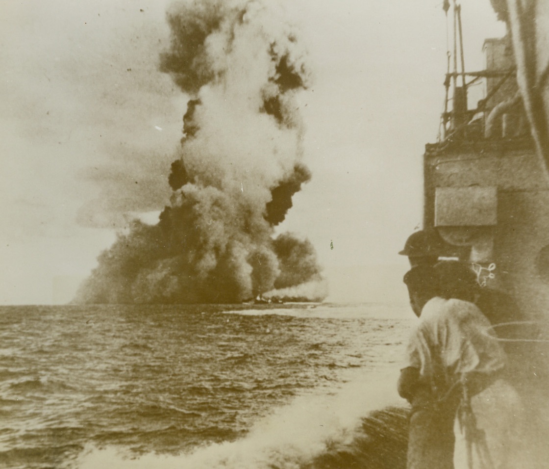 “BARHAM” GOES UP IN SMOKE, 12/13/1943. MEDITERRANEAN—Huge clouds of black smoke mark the watery grave of the 31,100-ton British battleship “Barham,” which blew up when hit by four enemy torpedoes off the Libyan coast on Nov. 25th, 1941. The vessel sank 4 minutes and 45 seconds after the first torpedo entered her side. Only 303 of her complement of 1172 men were saved. Photo, which was just released by the censor, was made from an Australian destroyer. Credit: Acme;