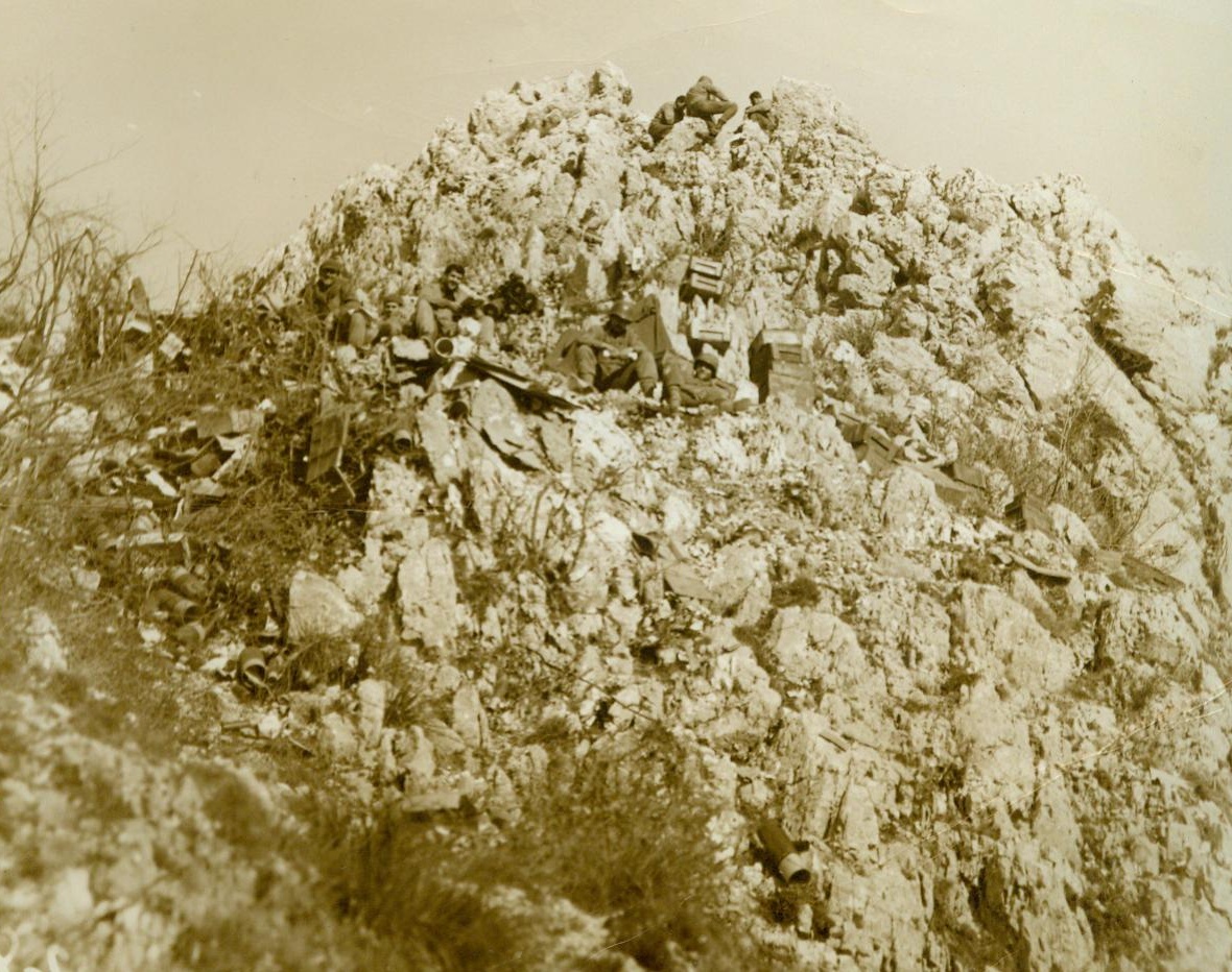 Italian Battlefield, 12/23/1943. Venafro, Italy – Here’s a sample of the rough, rugged terrain over which American doughboys are fighting in Southern Italy as they march toward Rome. A few Yanks squat for a rest on the rocky spot – An outpost on Venafro Ridge – As their buddies climb over the top. Credit Line (Photo By Bert Brandt, ACME Photographer for War Picture Pool). 12/23/43;