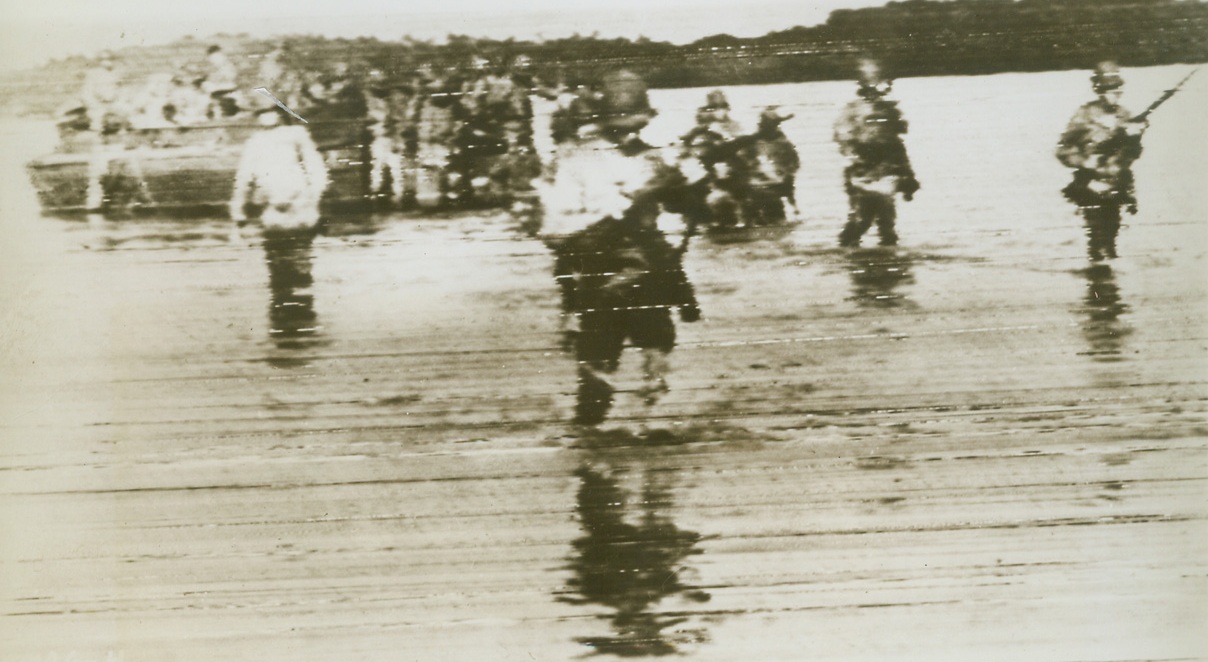 INVADERS WADE ASHORE, 12/18/1943. ARAWE, NEW BRITAIN—Streaming from their landing barge, American troops wade through the shallow waters off the shore of Arawe to complete the Allied invasion of New Britain. Although the invaders were bombed and strafed by the enemy as t hey landed, casualties were extremely light. Credit: Photo by Tom Shafer, Acme photographer for War Picture Pool;