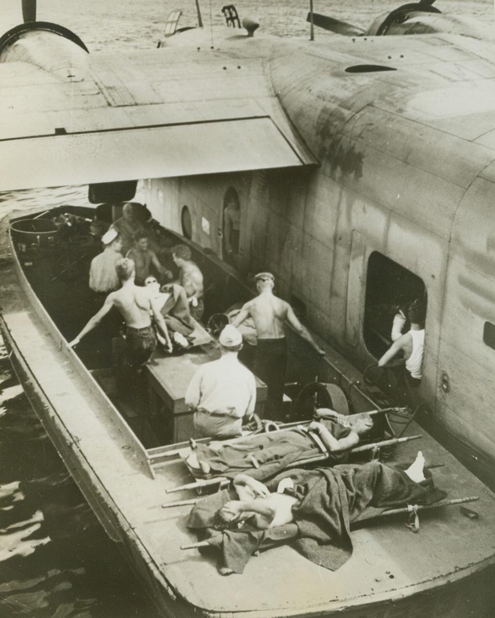 Back from Makin, 12/31/1943.  Just off Makin Island, U.S. Coast Guardsmen carefully transfer wounded Marines from a landing barge to a Navy plane which will speed them to hospital bases located in safer territory. A first aid station was set aboard a Coast Guard transport which operated as a unit in the Navy Task Force. Credit: U.S. Coast Guard photo from ACME;