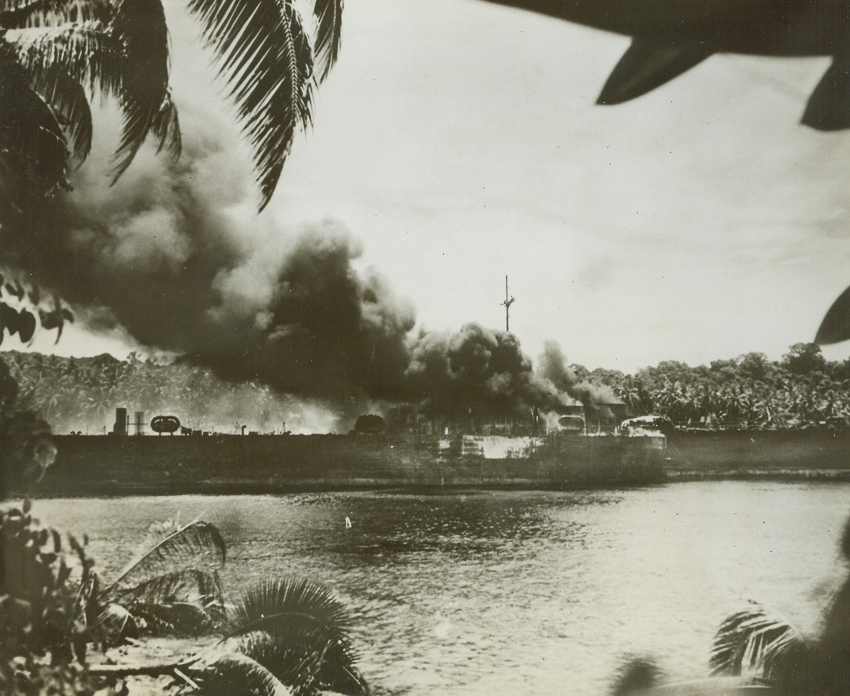 One for the Nips, 12/29/1943. South Pacific – Smoke pours from the blistered stern of an Allied LST (Landing Ship-Tanks), after a Japanese plane scored a hit during an attack on a South Pacific island in the combat zone where the LST was unloading its cargo. A sister ship (right background) stands by as its crew plays a stream of water on the burning vessel. Credit: U.S. Marines Corps photo from ACME;