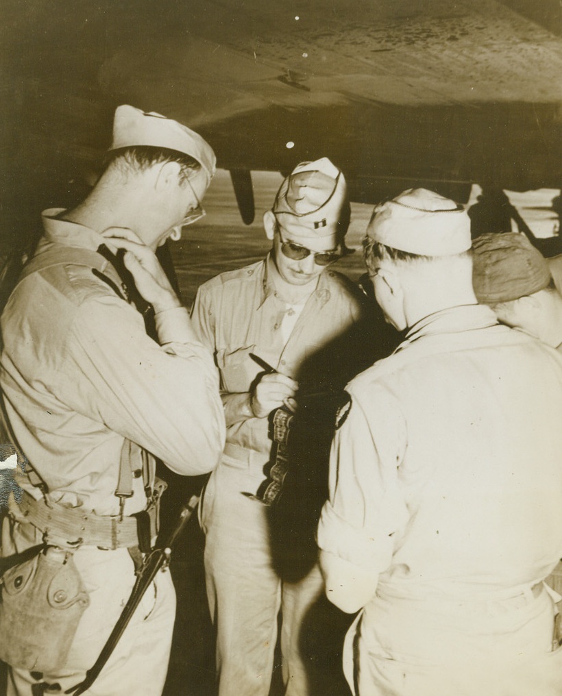 An Old Airways Custom, 12/8/1943. Hawaii: Lt. Col. James Roosevelt, left, observer in the Makin Campaign, watches his “Short-Snorter” Bill being signed, after arriving on ATC Hospital Plane at Hickam Field, T.H. Credit: ACME;