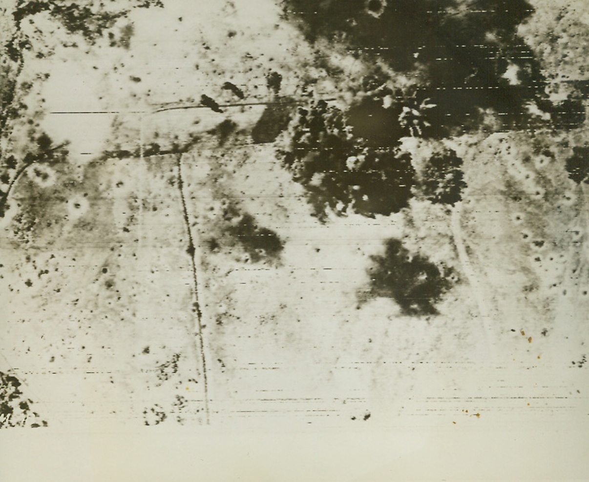 Yanks Wreck Cape Gloucester Field, 12/28/1943. This photo, flashed to the United States by radiotelephoto, shows bombs from U.S. B-24 Liberator and B-25 Mitchell Bombers, exploding on the Jap airfield at Cape Gloucester. The field is shown pitted with shell craters from almost daily bombing by Allied planes since Dec. 1st. In upper right, bombs burst on Nip planes which were trapped on the ground. These raids were in preparation for landings by American Marines who, it was announced today, had made their second landing in the Cape Gloucester area. Credit: U.S. Signal Corps Radiotelephoto from ACME;