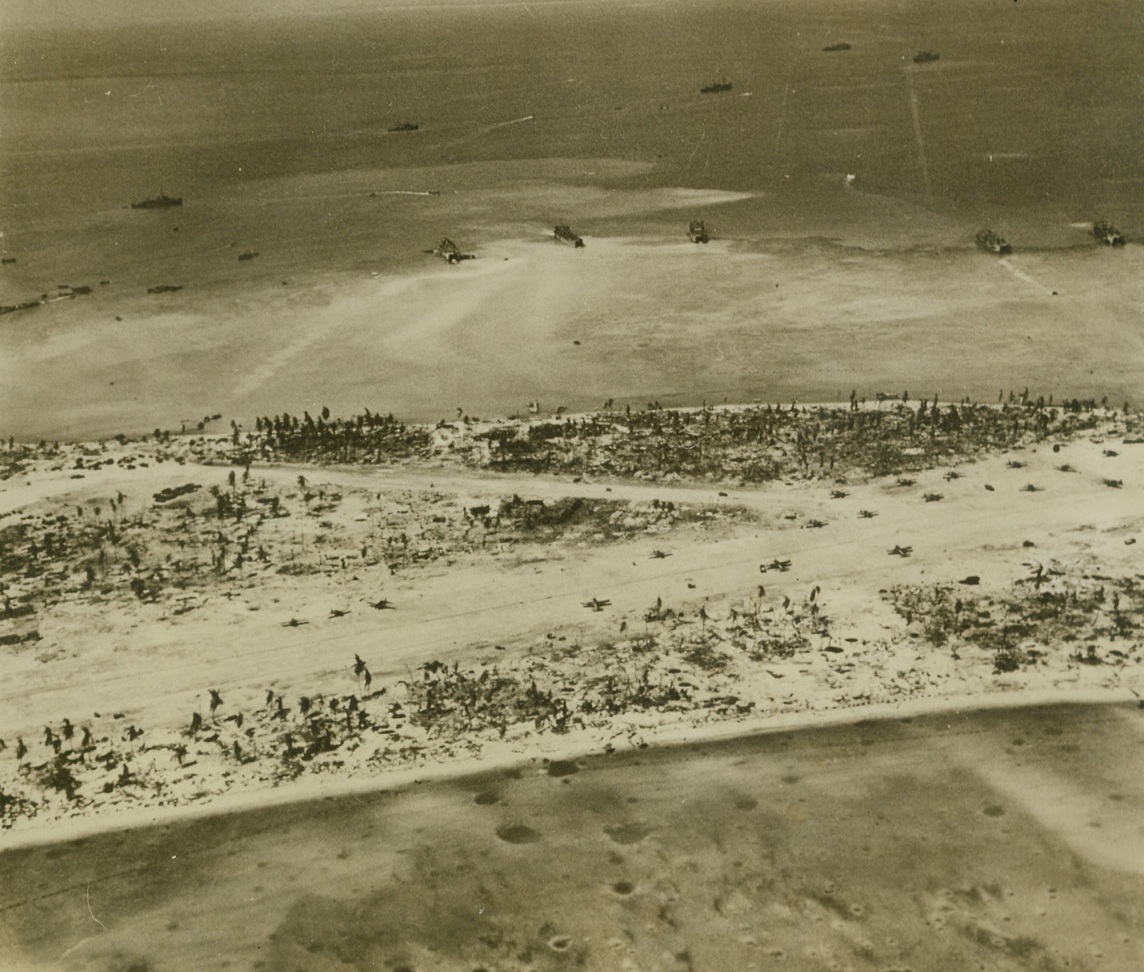 After the Battle at Tarawa, 12/16/1943. CME; Betio Island, part of the Tarawa group, shows considerable evidence of the terrific fire concentrated on it during the battle for Tarawa, by Allied Sea and Air Forces. Shell craters pock the tiny strip of land and the shallow water near it, and palm trees have been stripped of their foliage by the fury of the battle. Planes along the air strip are American planes Credit;